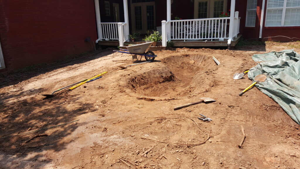 A dirt yard with a wheelbarrow and tools.