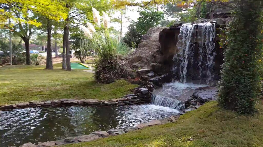 A waterfall that is in the middle of some grass.