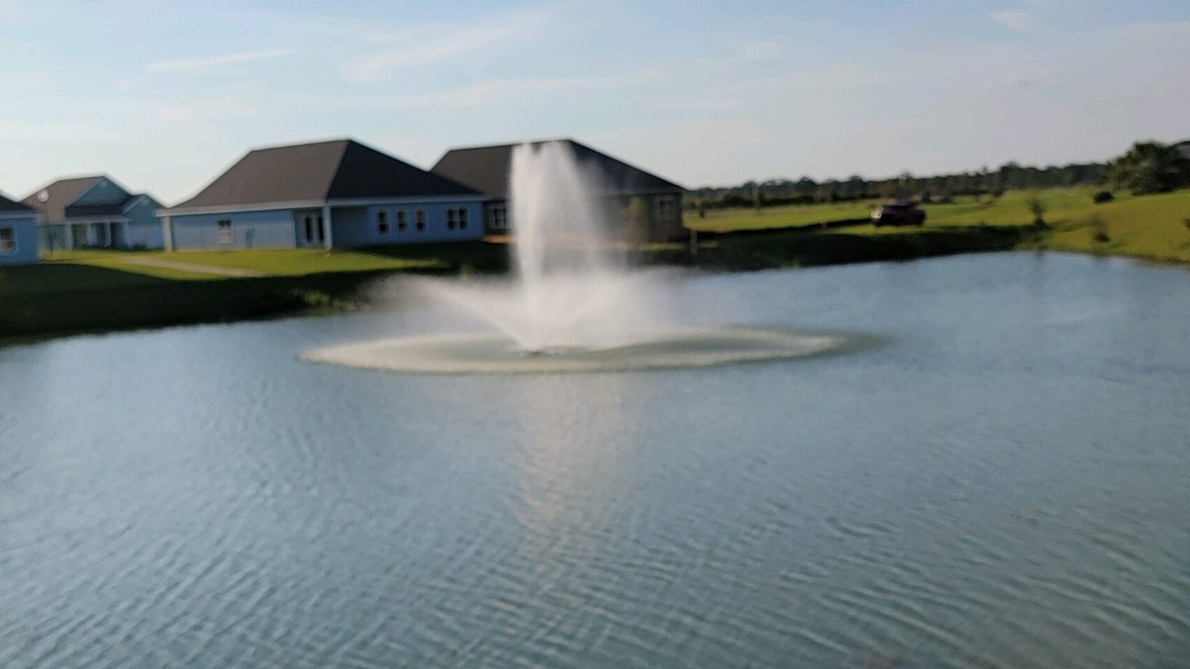 A fountain in the middle of a lake with water splashing.