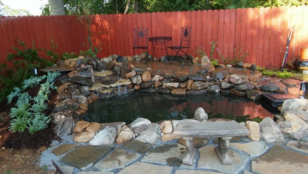 A pond with rocks and water features in the back yard.