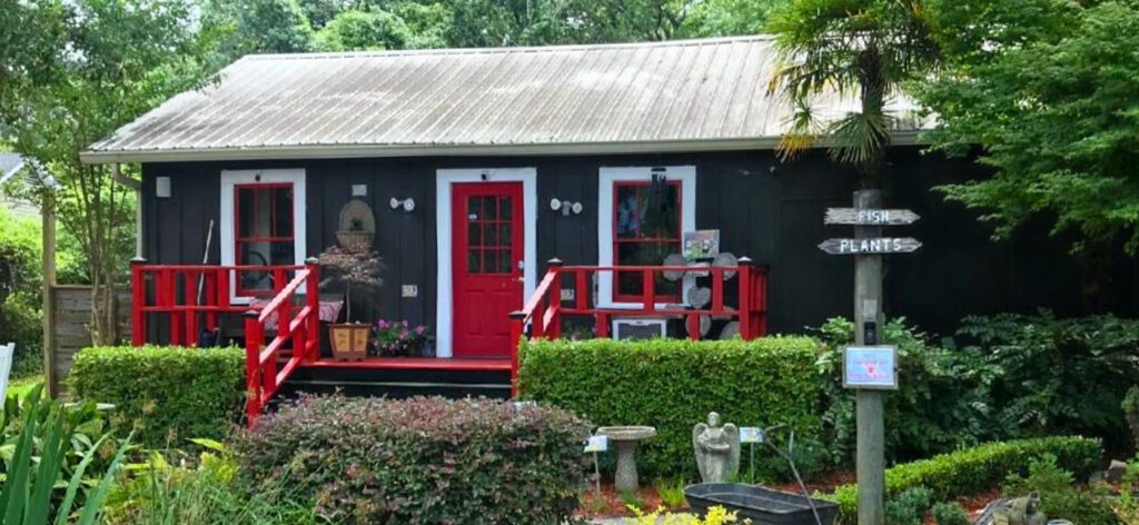 A black and red house with bushes around it