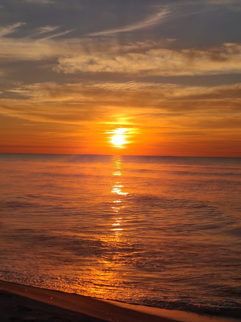 A sunset over the ocean with orange and yellow colors.